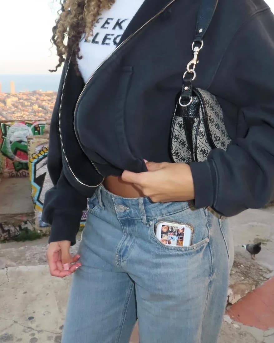 Annah in a black jacket and jeans, with one of the pink cards in her pocket